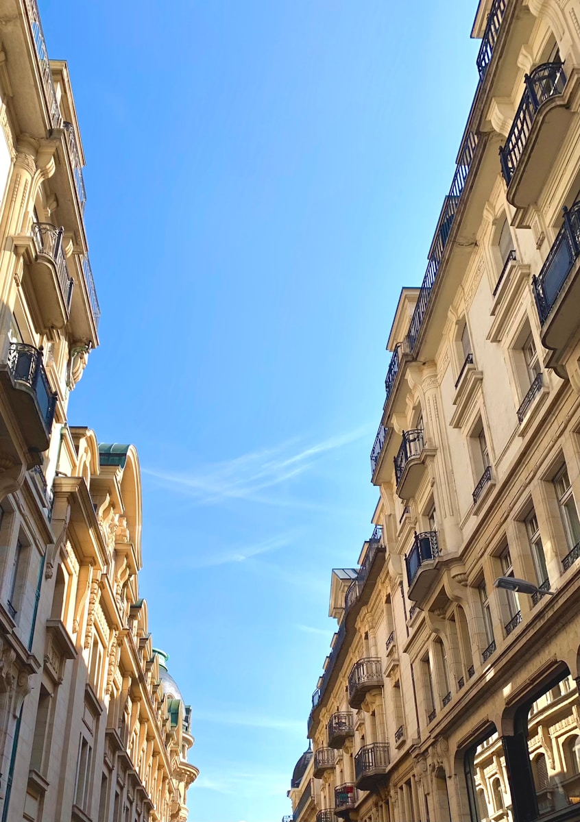 low angle photography of beige concrete building under blue sky during daytime