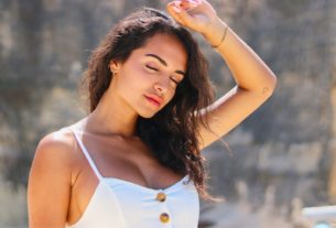 woman in white spaghetti strap top holding her hair